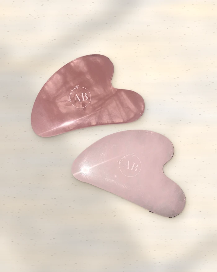 Rose quartz and clear quartz gua sha on stone