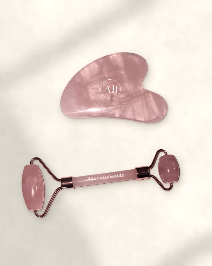 Rose quartz roller and gua sha on stone